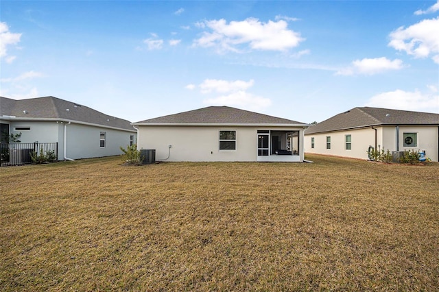 rear view of property featuring cooling unit and a lawn