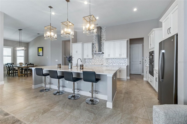 kitchen with white cabinets, stainless steel fridge, a kitchen breakfast bar, hanging light fixtures, and a large island