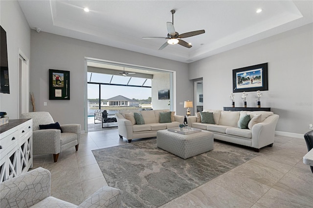 living room featuring ceiling fan, a raised ceiling, and a high ceiling