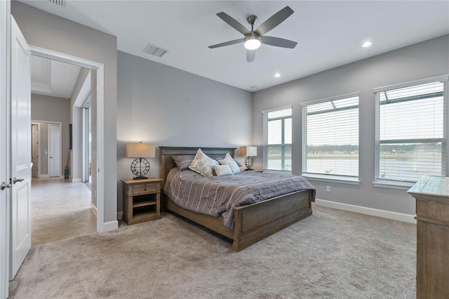 bedroom with a water view, light colored carpet, and ceiling fan