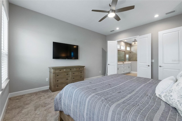 bedroom with ceiling fan, ensuite bath, and light carpet