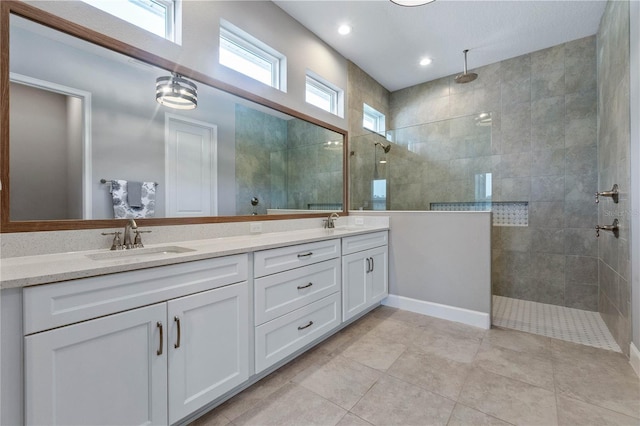 bathroom with tiled shower, vanity, and tile patterned flooring