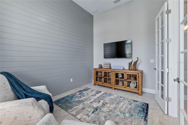 living area with wooden walls and french doors