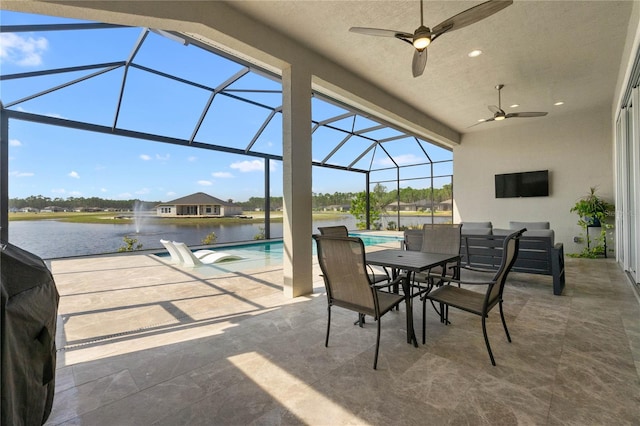 view of patio featuring a water view, ceiling fan, and glass enclosure