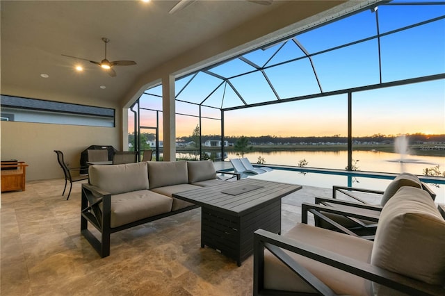 patio terrace at dusk featuring ceiling fan, a swimming pool, outdoor lounge area, a water view, and glass enclosure