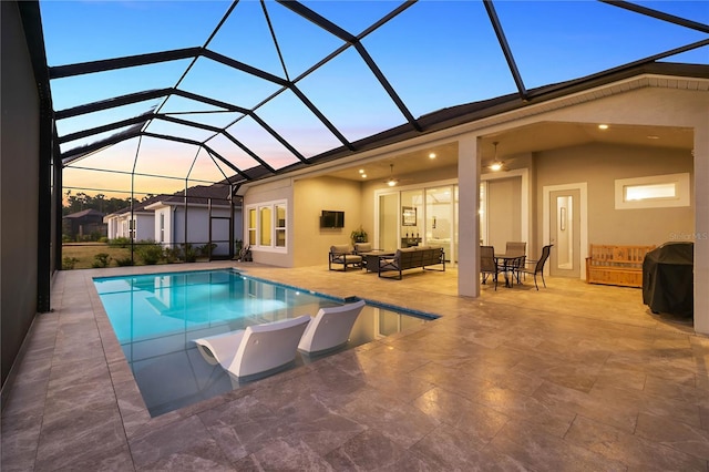 pool at dusk with an outdoor living space, a lanai, and a patio