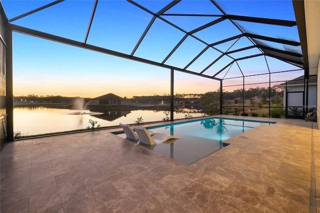 pool at dusk with a patio, a water view, and a lanai