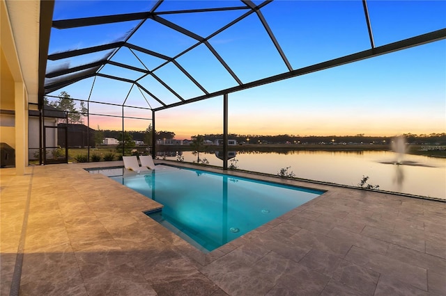 pool at dusk with a lanai, a patio area, and a water view