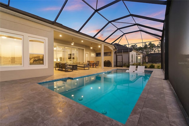 pool at dusk featuring a lanai, outdoor lounge area, and a patio area