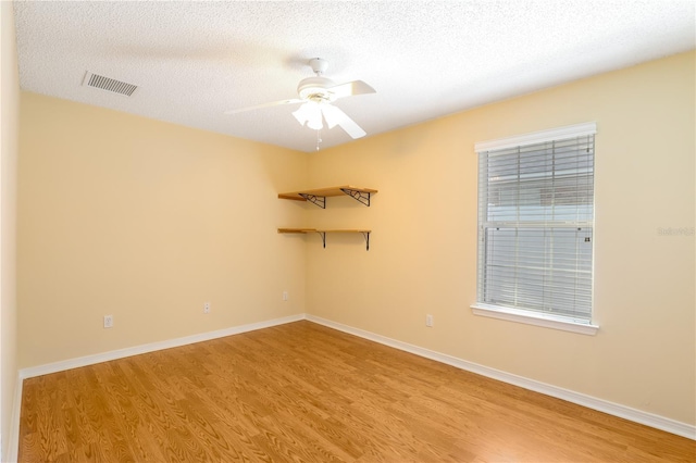 empty room with ceiling fan, a textured ceiling, and light wood-type flooring