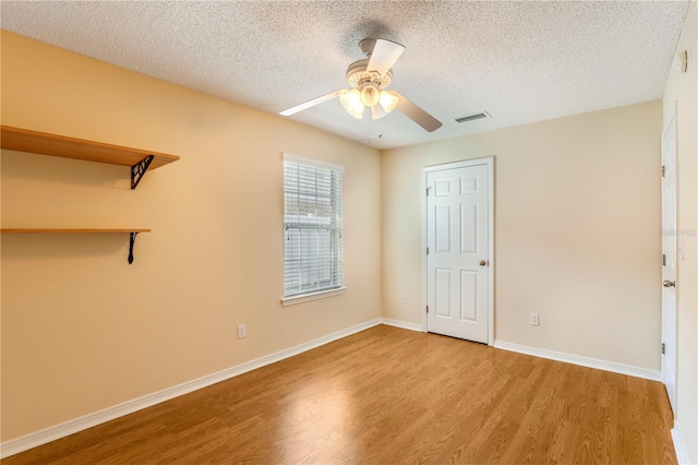 empty room featuring ceiling fan, a textured ceiling, and light wood-type flooring