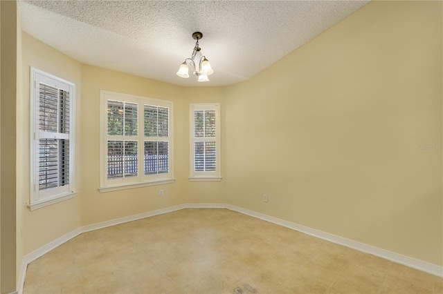 spare room featuring a notable chandelier and a textured ceiling