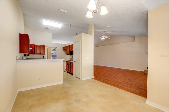 kitchen featuring lofted ceiling, kitchen peninsula, ceiling fan with notable chandelier, and a textured ceiling