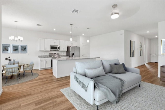 living room featuring an inviting chandelier and light hardwood / wood-style flooring