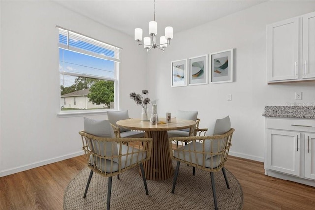 dining area with wood-type flooring and a notable chandelier