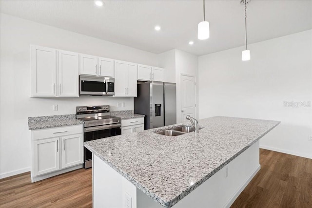 kitchen featuring hanging light fixtures, appliances with stainless steel finishes, sink, and a center island with sink