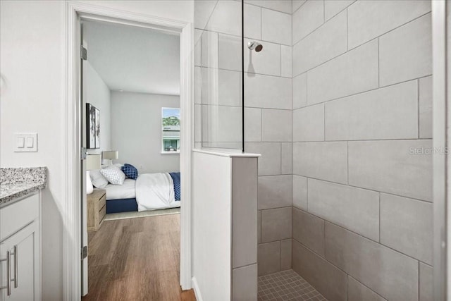 bathroom with vanity, wood-type flooring, and a tile shower