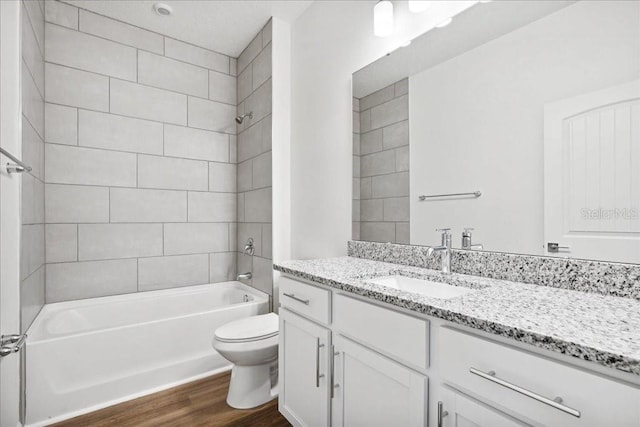 full bathroom featuring tiled shower / bath combo, vanity, hardwood / wood-style floors, and toilet