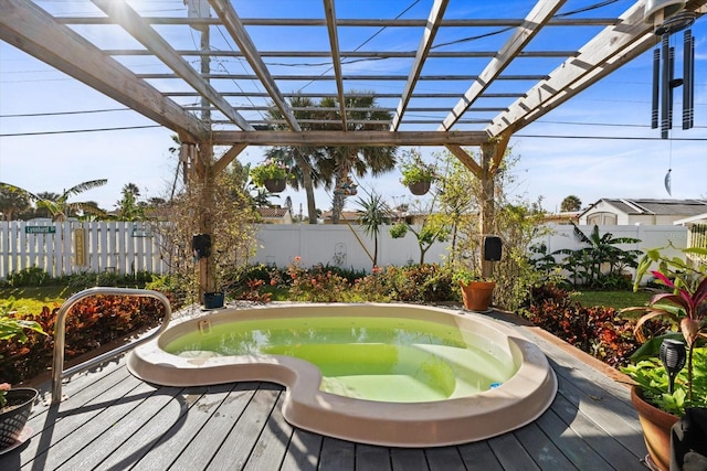 deck featuring an outdoor hot tub and a pergola