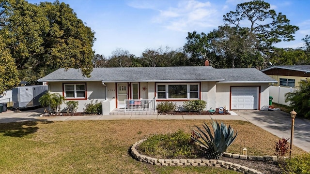 ranch-style home featuring a garage, covered porch, and a front lawn