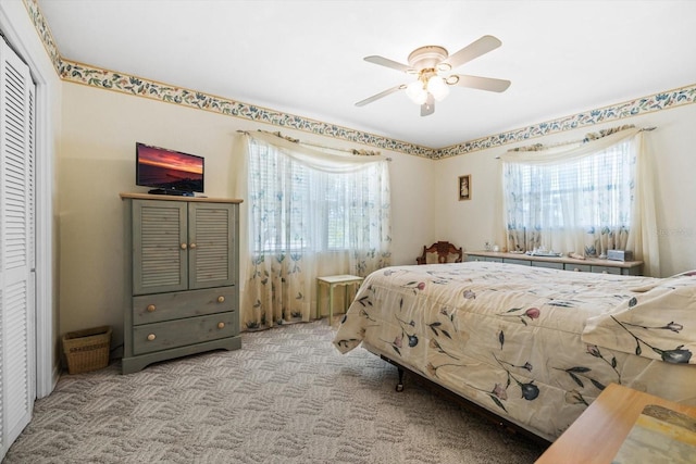 carpeted bedroom featuring multiple windows, ceiling fan, and a closet