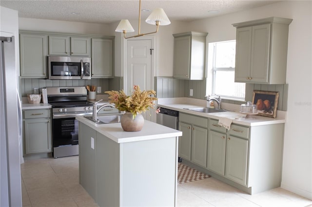 kitchen featuring stainless steel appliances, sink, a center island with sink, and decorative light fixtures