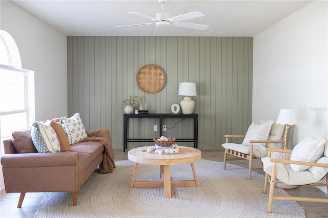 living area featuring ceiling fan, light hardwood / wood-style floors, and a textured ceiling