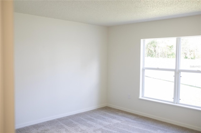 carpeted empty room featuring a textured ceiling