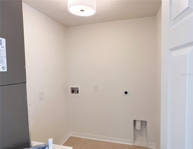 laundry room with hookup for a washing machine, electric dryer hookup, light tile patterned floors, and a textured ceiling