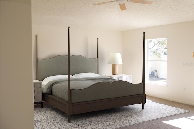 carpeted bedroom featuring ceiling fan and a textured ceiling