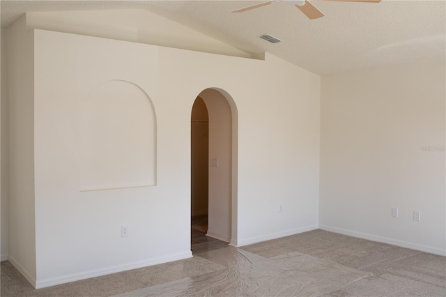 carpeted empty room featuring ceiling fan, lofted ceiling, and a textured ceiling