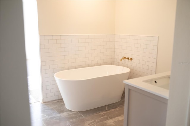 bathroom with a tub, sink, and tile walls