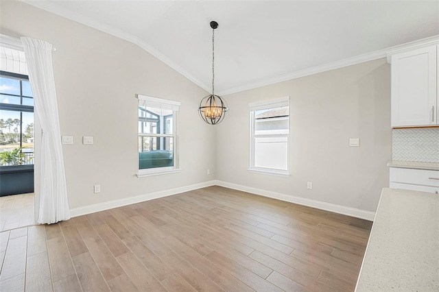 unfurnished dining area featuring an inviting chandelier, lofted ceiling, crown molding, and light wood-type flooring