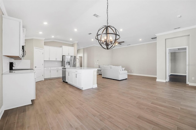 kitchen featuring light hardwood / wood-style flooring, an island with sink, white cabinets, pendant lighting, and backsplash