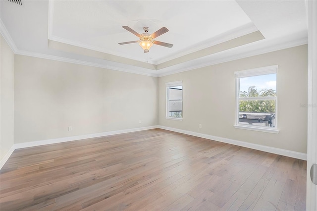 spare room with a tray ceiling, ornamental molding, light hardwood / wood-style floors, and ceiling fan