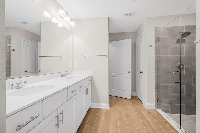 bathroom featuring vanity, a shower with shower door, hardwood / wood-style floors, and a textured ceiling