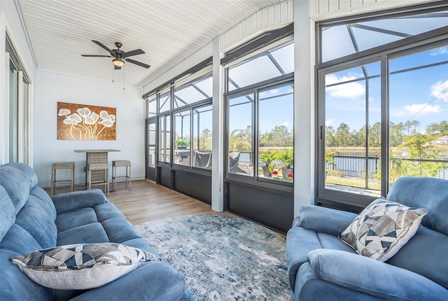 sunroom with ceiling fan and a water view