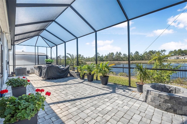 view of patio with a water view, a lanai, central AC unit, and a fire pit