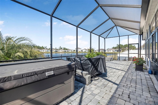 view of patio with a lanai, a hot tub, and a water view