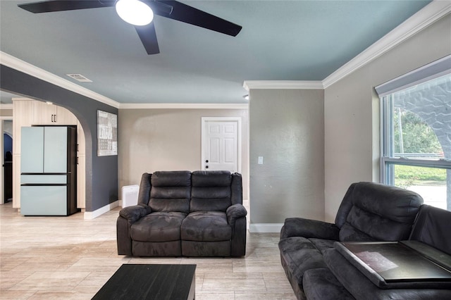 living area with arched walkways, ornamental molding, visible vents, and baseboards