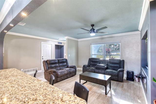 living room featuring light wood-style flooring, crown molding, visible vents, and baseboards