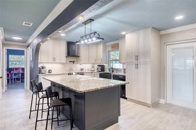 kitchen featuring a center island, black dishwasher, wall chimney range hood, light stone countertops, and decorative light fixtures