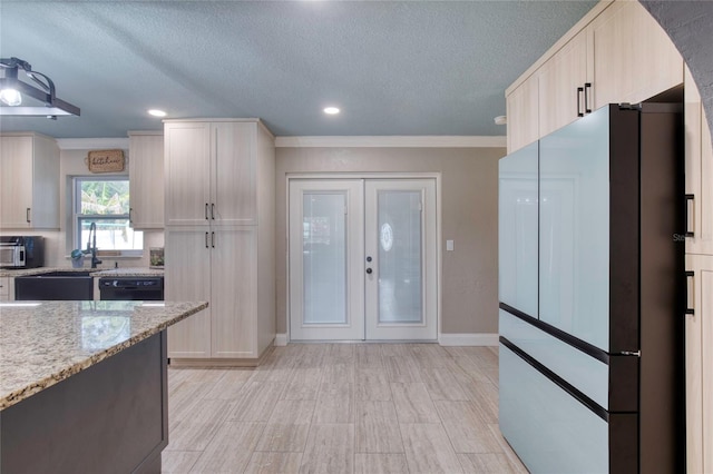 kitchen with a textured ceiling, french doors, freestanding refrigerator, light stone countertops, and light brown cabinetry