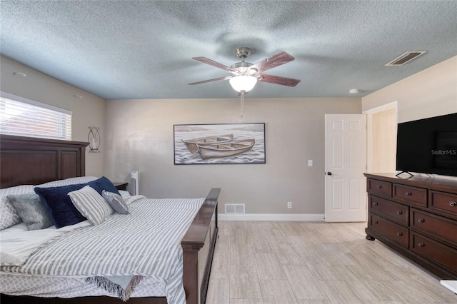 bedroom with a ceiling fan, light wood-type flooring, visible vents, and baseboards