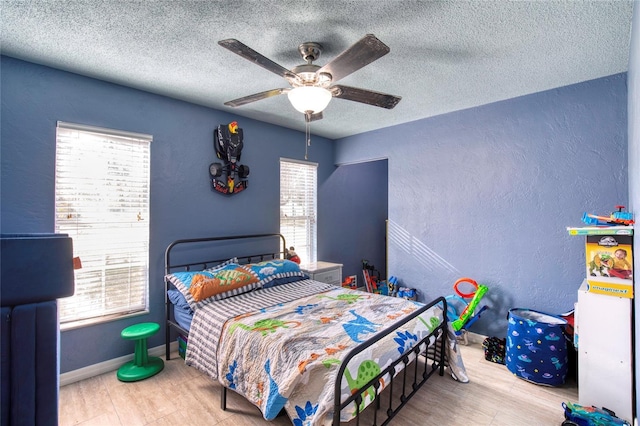 bedroom with a textured wall, a textured ceiling, baseboards, and ceiling fan