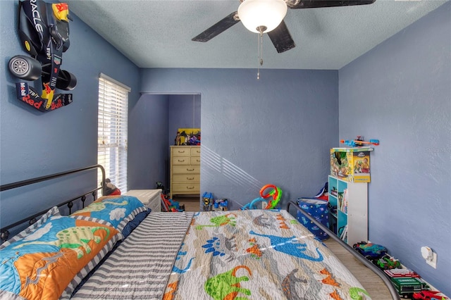 bedroom featuring a ceiling fan, a textured ceiling, and a textured wall