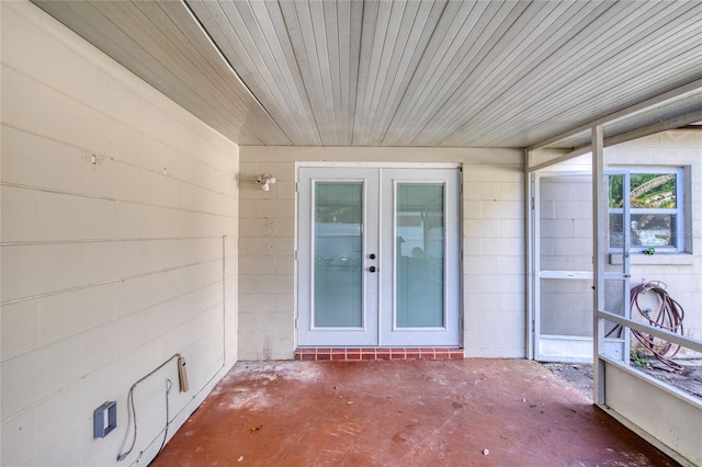 property entrance featuring french doors, concrete block siding, and a patio