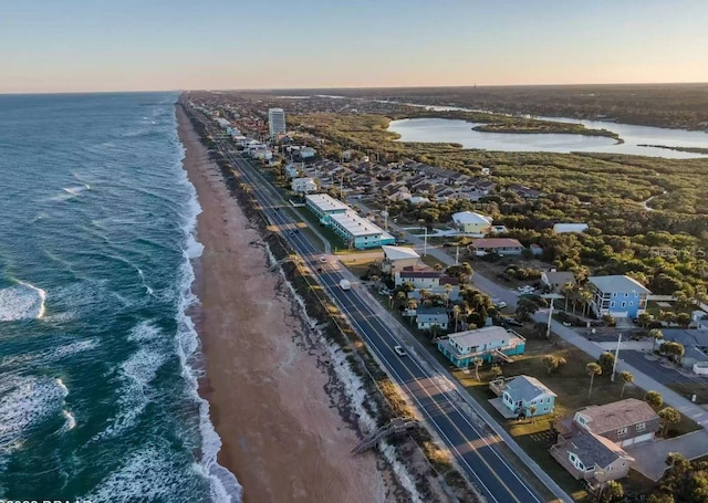 aerial view at dusk with a water view and a view of the beach