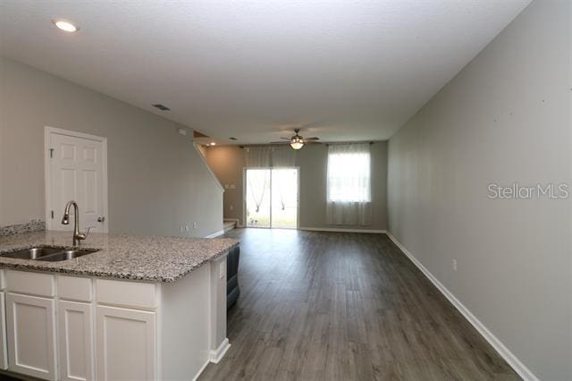 kitchen featuring sink, white cabinetry, light stone counters, dark hardwood / wood-style flooring, and ceiling fan