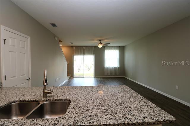 kitchen with dark hardwood / wood-style flooring, sink, ceiling fan, and light stone counters